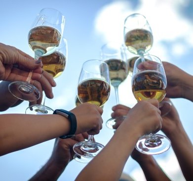 Gruppenerlebnis Schlenderweinprobe - Gruppe hält Weingläser in die Höhe vor blauem Himmel