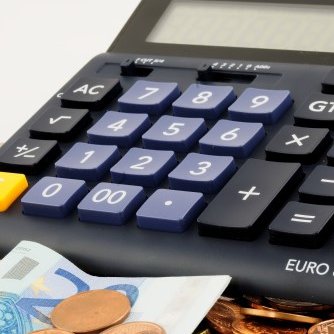 Grundsteuer - Taschenrechner auf Euro-Münzen und -geldscheinen liegend