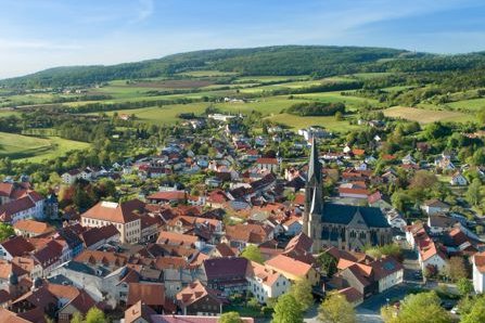 Drohnenflugaufnahme der Stadt Tann (Rhön) mit Blick-Richtung Norden. Im Hintergrund Felder und Wiesen sowie die grünen Berge der Kuppenrhön