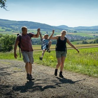 Natur auf der Spur - Familie mit kleinem Kind bei Wanderung vor dem Hintergrund des Ulstertales