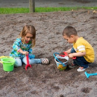 Spielplätze - kleines Mädchen und Junge spielen im Sandkasten