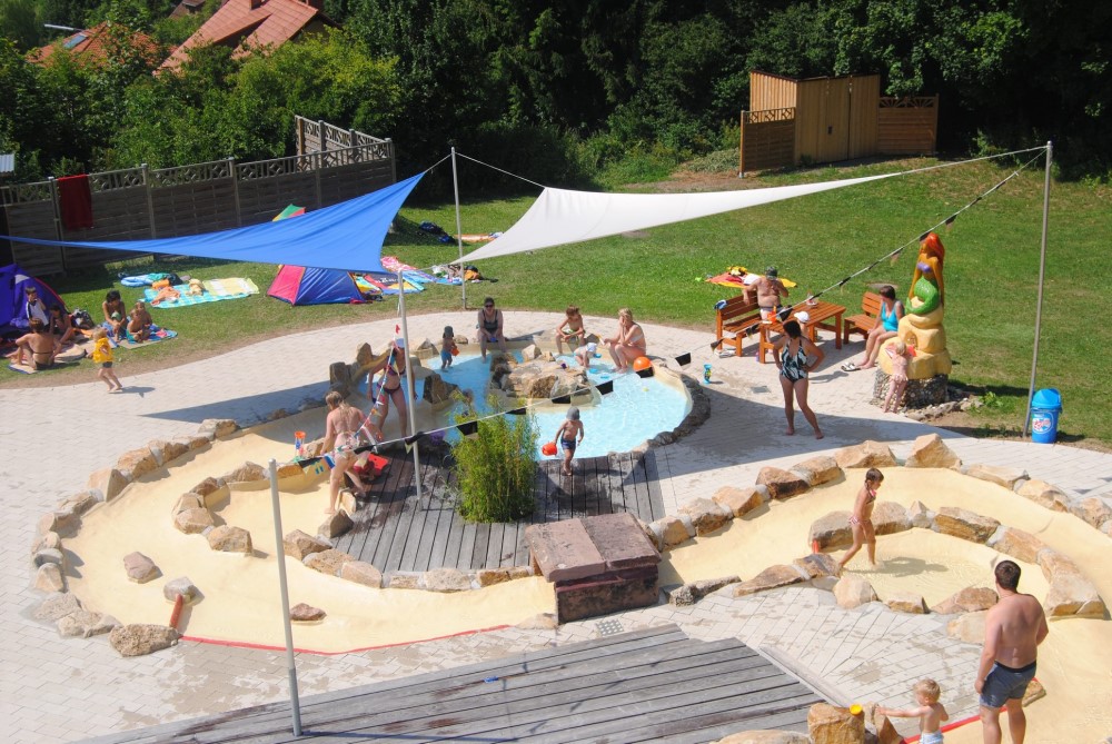 Wasserspielgarten des Tanner Geriethbades mit Sonnensegel und Eltern mit Kindern