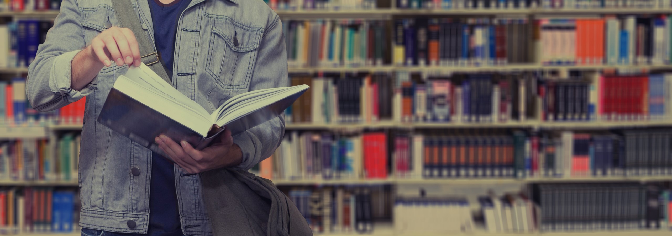 Bücherei - Panoramaschnitt Student vor Bücherregal blättert in Buch