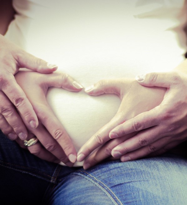 Schwangerschaft - Mutter mit Babybauch, Hände des Paar formen Herz auf dem Bauch